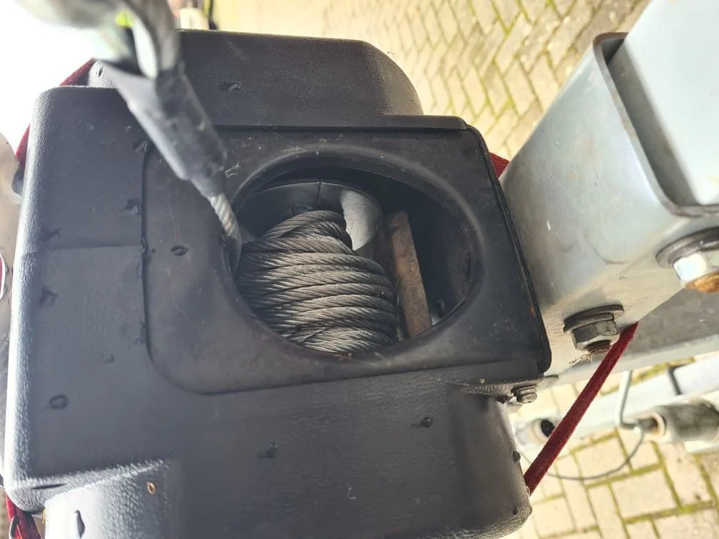 Coiled anchor rope stored in black plastic compartment of boat equipment.