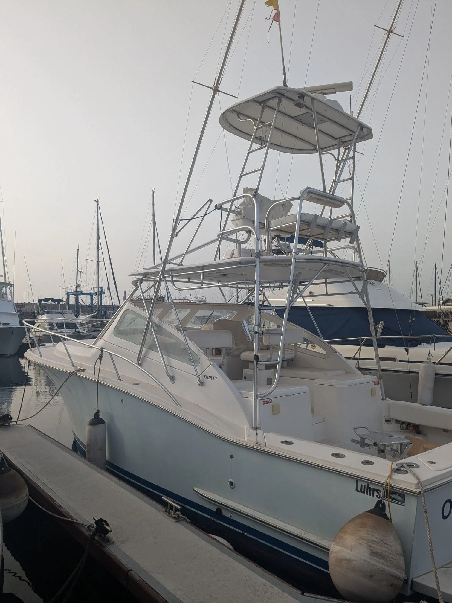 Sport fishing boat moored at St. Petersburg marina with twin towers and rigging visible.