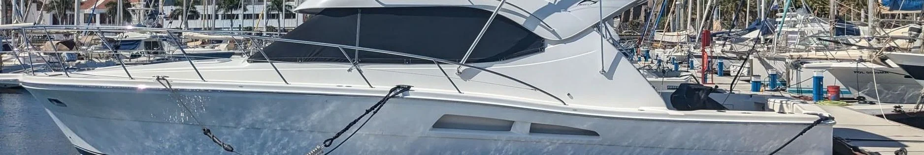 Moored recreational fishing boat with white hull and black canvas canopy at St. Petersburg marina.
