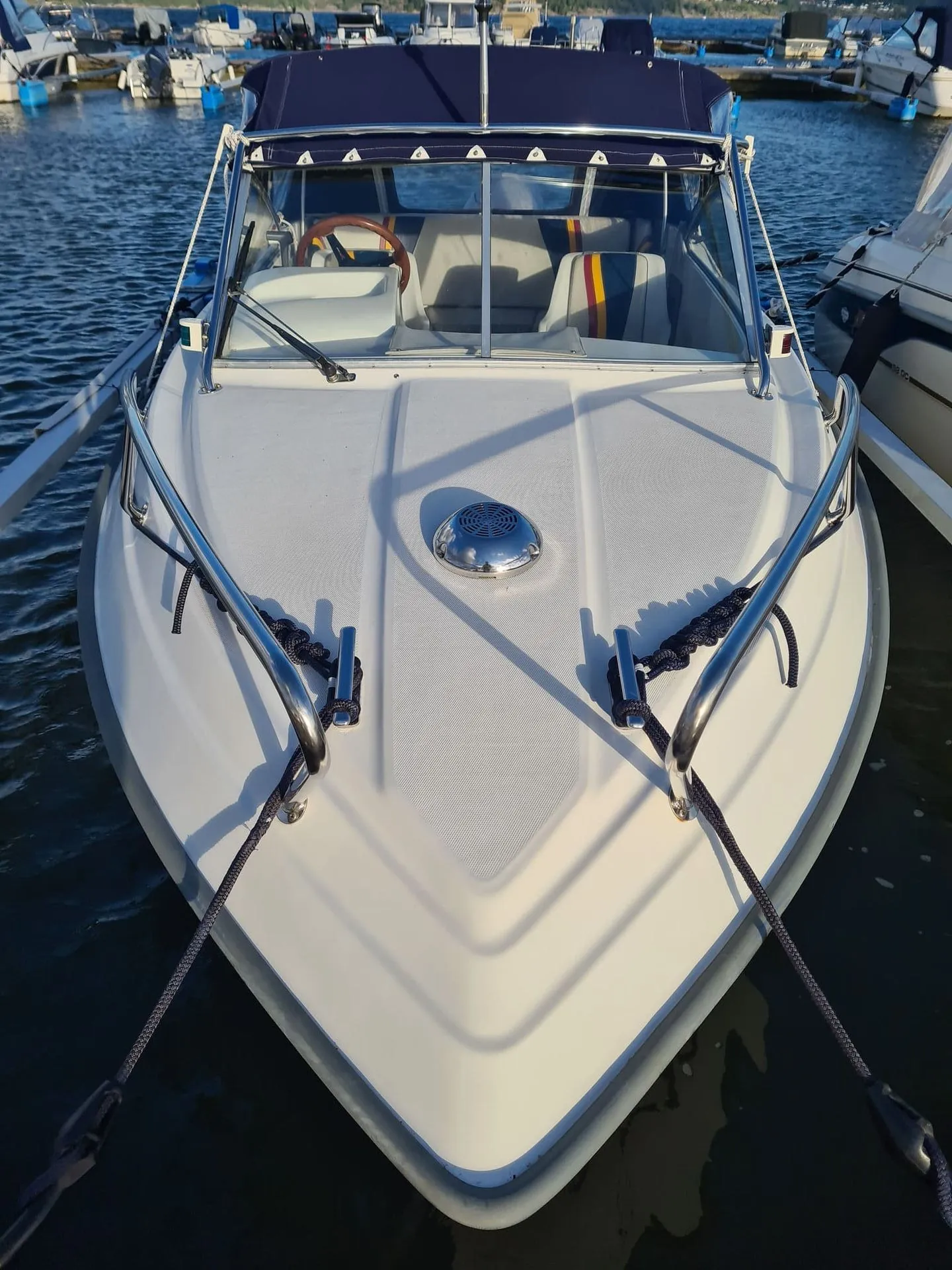 White recreational fishing boat moored at St. Petersburg marina with outboard motor visible and cleats secured.