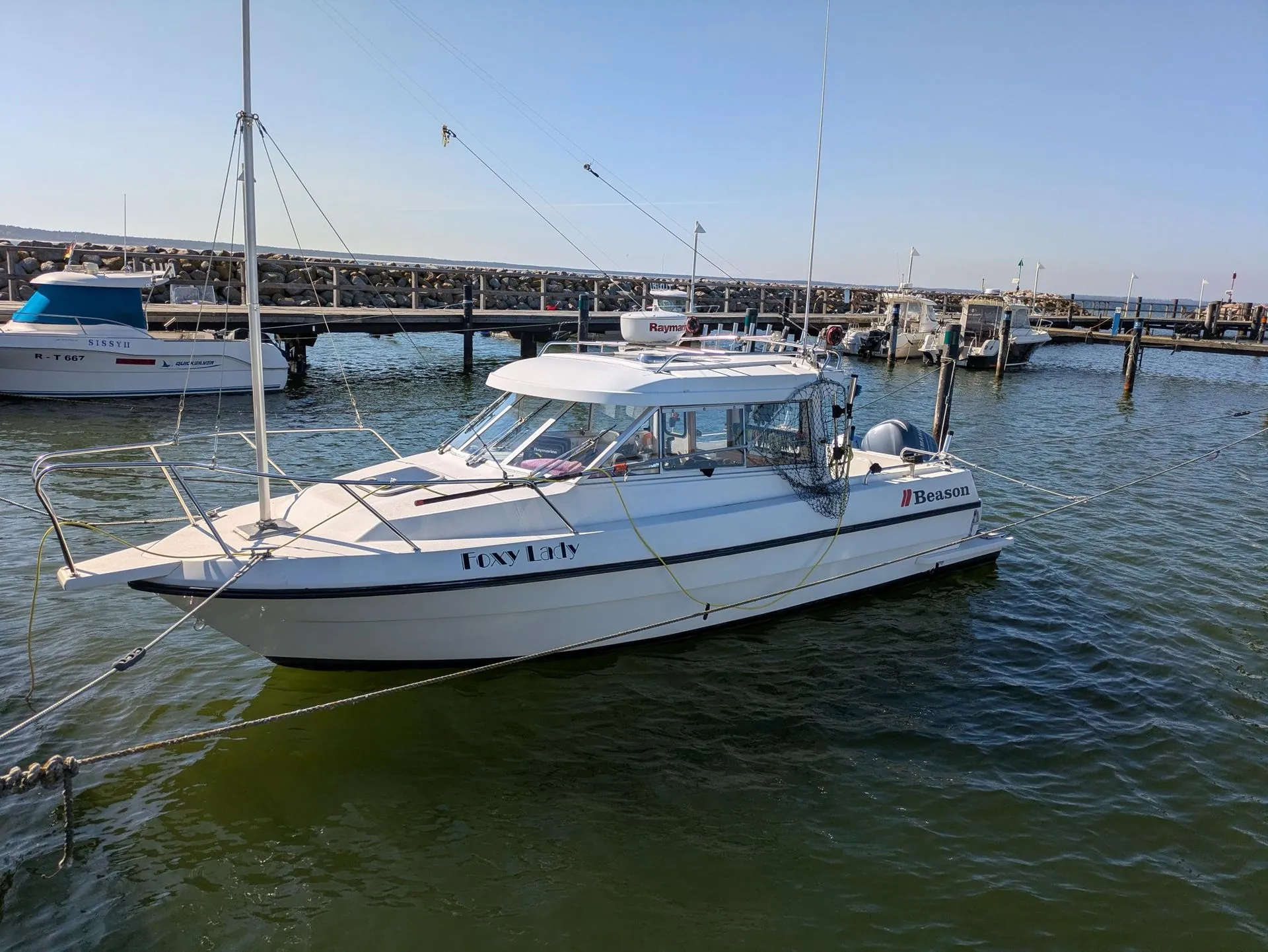 Recreational fishing boat moored in St. Petersburg marina with multiple vessels and wooden docks visible.