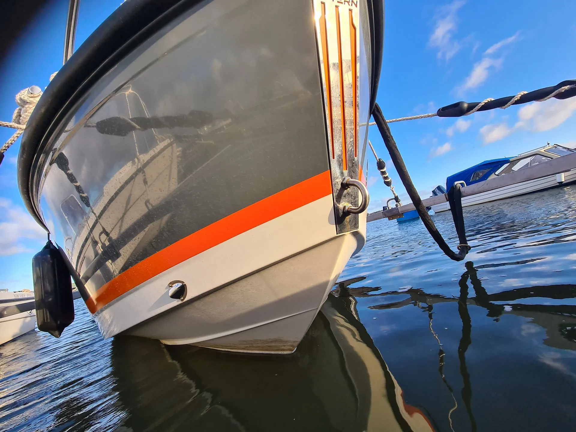 Recreational fishing boat moored in calm Florida waters with orange and white hull stripe visible.