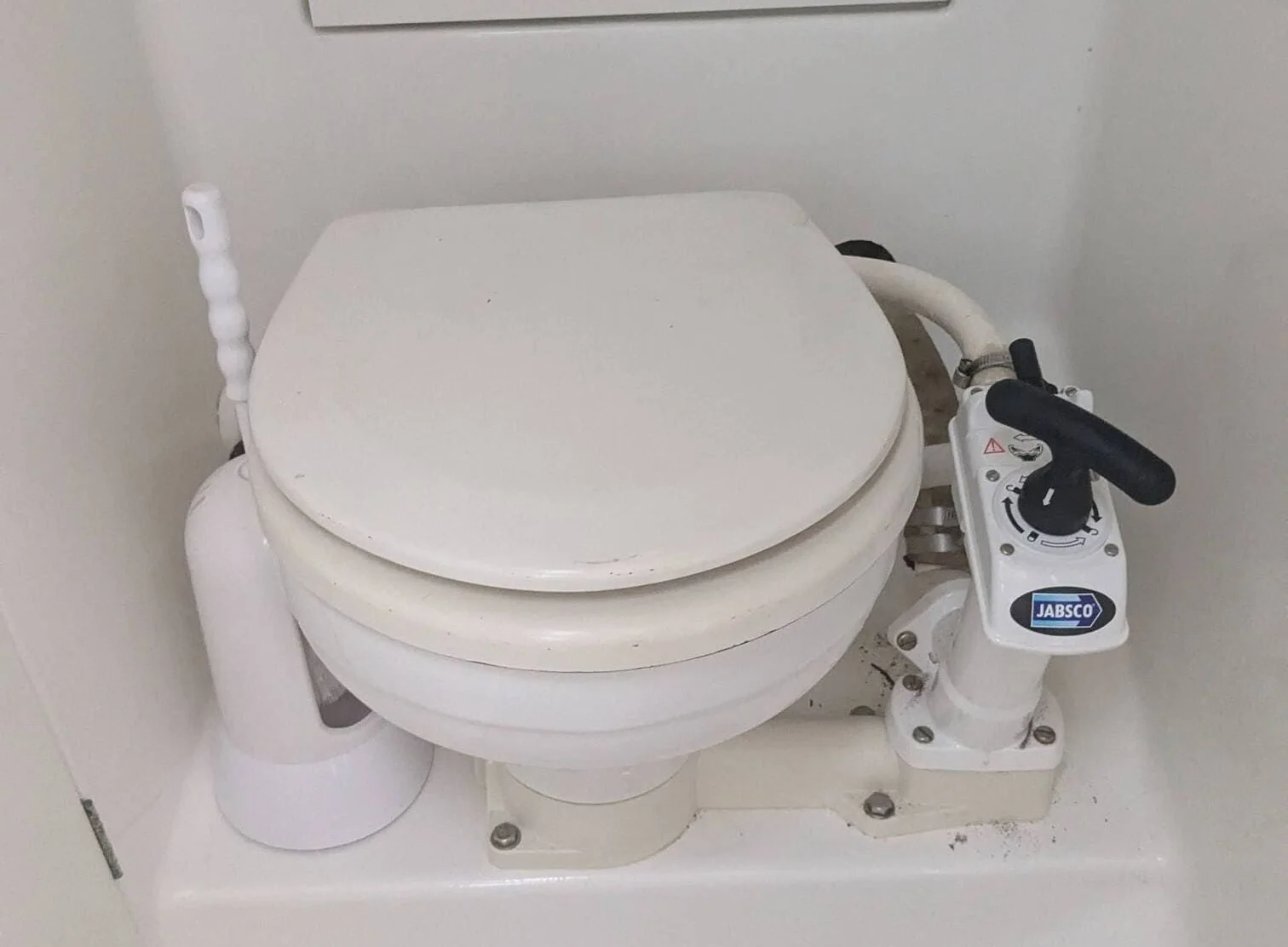 Marine toilet with manual pump flush system installed in boat cabin.