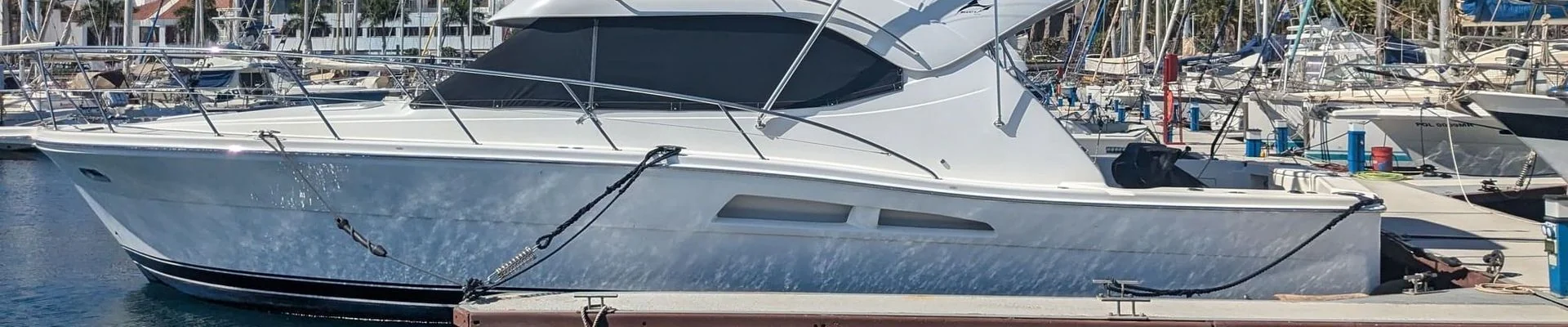 Moored yacht with weathered hull at St. Petersburg marina dock, multiple sailboats in background.