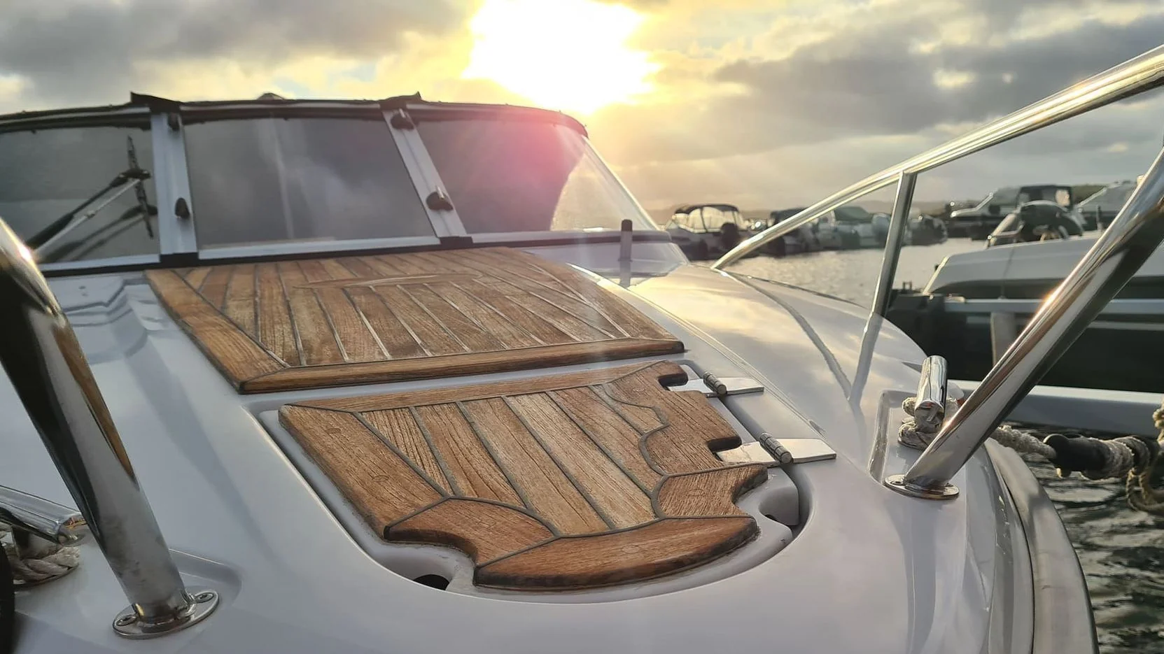Boat deck with teak wood hatches and canvas cover at sunset, moored in St. Petersburg marina.