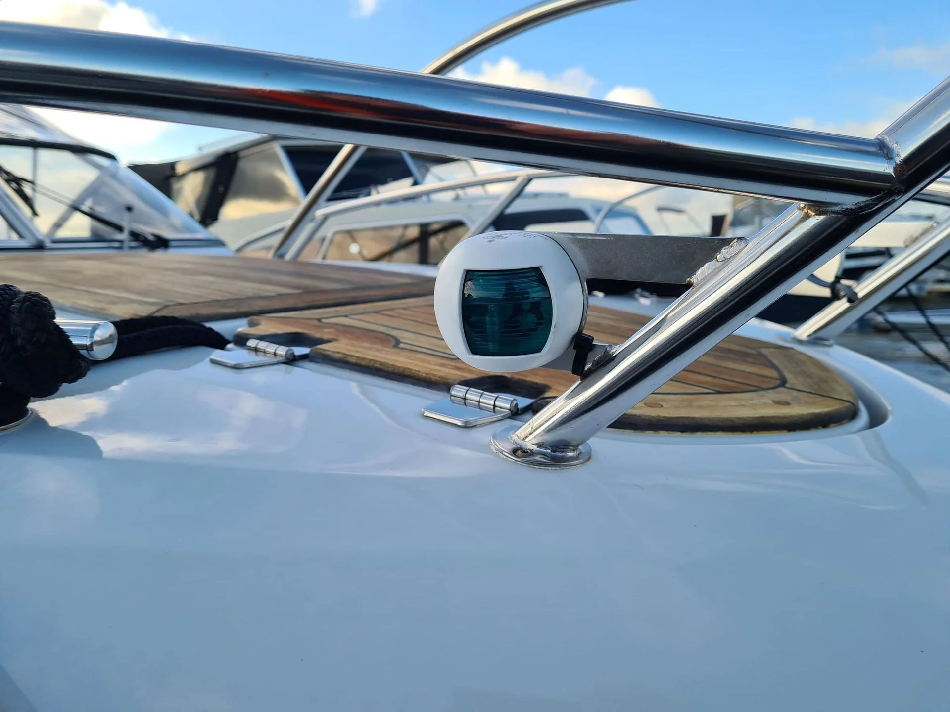 Navigation display and steering components on boat console with chrome railings and blue sky.