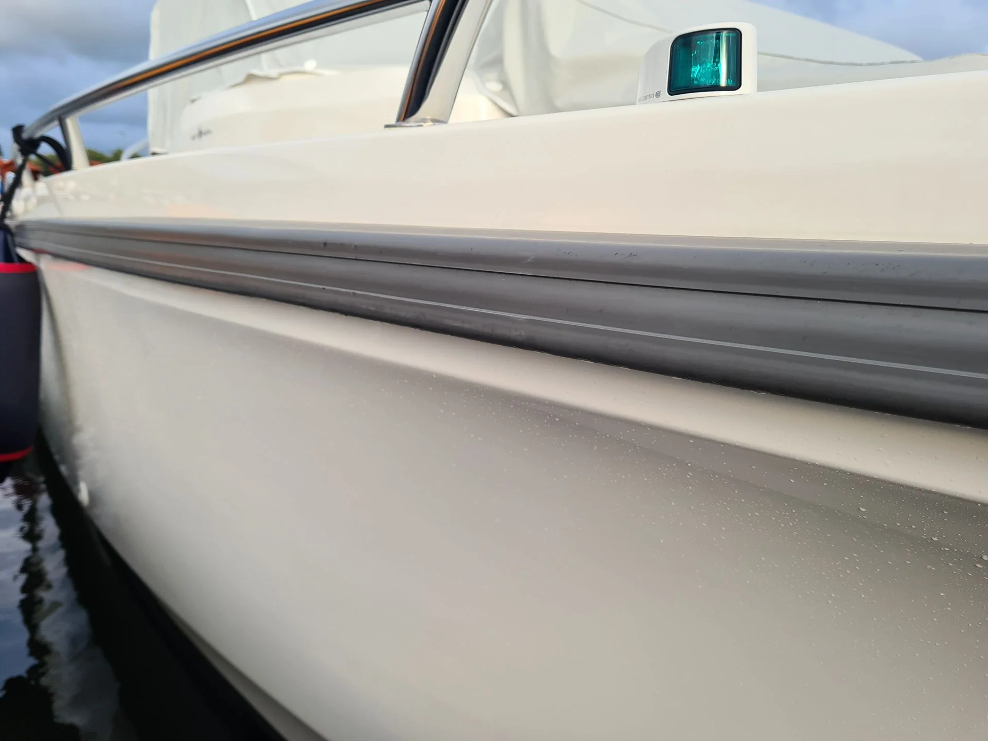 Boat hull side profile showing white fiberglass with gray rubbing strake and minor surface salt deposits.