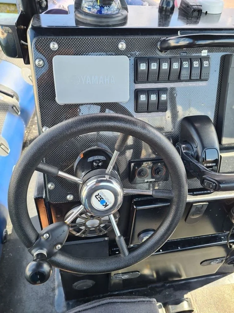 Jet ski dashboard with steering wheel, Yamaha control panel, and switch array in bright sunlight.
